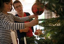 Mutter und Tochter schm&uuml;cken gemeinsam den Weihnachtsbaum - Mascha Brichta/dpa-tmn