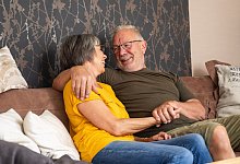 Älteres Paar sitzt lächelnd auf einer Couch - Benjamin Nolte/dpa-tmn
