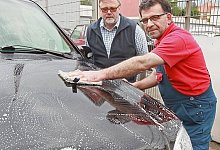 Erst einweichen, dann abwaschen: Mahmut Toker reinigt die Motorhaube vomHonigtau. Hinter ihm steht Kunde Axel Kelch aus Hiddenhausen. - Frank-Michael Kiel-Steinkamp