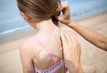 Eine Person cremt einen Kinderr&uuml;cken ein - Florian Schuh/dpa-tmn