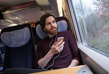 Mann sitzt in einem ICE - Christin Klose/dpa-tmn