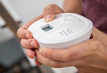 Mann testet einen Kohlenmonoxidmelder - Christin Klose/dpa-tmn