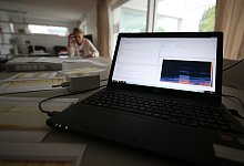 Steffi Runge sitzt am Wohnzimmertisch, auf dem Messdiagramme und Aktenordner liegen. Im Vordergrund steht ein Messcomputer mit einem speziellen Mikrofon. - Gerald Dunkel