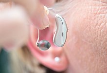 Eine Frau h&auml;lt ein H&ouml;rger&auml;t vor ihr Ohr - Bernd Wei&szlig;brod/dpa/dpa-tmn