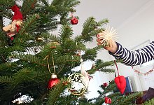 Mädchen schmückt einen Weihnachtsbaum - Bodo Marks/dpa-tmn