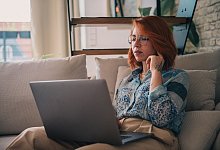 Eine Frau sitzt auf der Couch und nutzt einen Laptop - Zacharie Scheurer/dpa-tmn