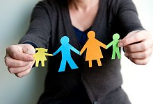 Eine Frau hält eine Familie aus buntem Papier - Mascha Brichta/dpa-tmn