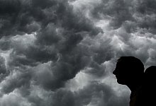 Ein Mann steht unter einem stürmischen Himmel - Julian Stratenschulte/dpa/dpa-tmn