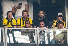 Besucher verfolgen das Spiel auf einer Tribüne für BVB-Fans, vorne sitzt der ehemalige Spieler Kevin Großkreutz (M). - Bernd Thissen/dpa