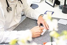 Eine Person im Kittel schreibt etwas auf - Benjamin Nolte/dpa-tmn