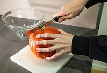 Frau schneidet einen Kürbis - Christin Klose/dpa-tmn