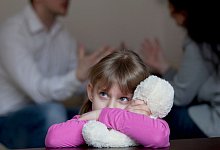 M&auml;dchen mit Teddy w&auml;hrend im Hintergrund Mann und Frau streiten - Silvia Marks/dpa-tmn