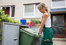 Eine Frau rangiert eine Biomülltonne - Christin Klose/dpa-tmn