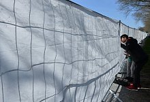 Symbolbild: Ein Junge schaut durch die Sichtabsperrung eines Zauns bei einem Fu&szlig;ballspiel. - picture alliance / dpa