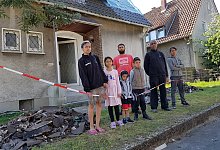 Nichts mehr zu retten: Die beiden Familien stehen vor den Tr&uuml;mmern des Brandhauses. - Marianne Schwarzer
