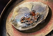 Schmuck liegt in einer Tonschale mit Blattmuster - Franziska Gabbert/dpa-tmn