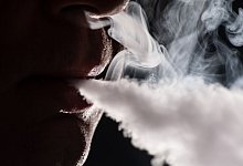 Mann atmet Dampf einer E-Zigarette aus - Franziska Gabbert/dpa-tmn