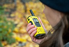 Eine Frau spricht in ein Walkie-Talkie in ihrer Hand - Nico Tapia/dpa-tmn
