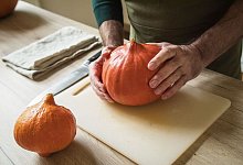 Ein Mann hält einen Hokkaido-Kürbis in den Händen - Christin Klose/dpa-tmn