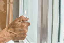 Eine Frau h&auml;lt ein Feuerzeug an ein Fenster - Christin Klose/dpa-tmn