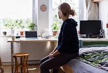 Eine Studentin sitzt auf dem Bett in ihrem WG-Zimmer - Michael Matthey/dpa