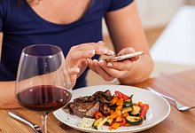 Eine Person mit Smartphone am Tisch - Christin Klose/dpa-tmn