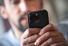 Ein Mann schaut auf ein Smartphone - Sina Schuldt/dpa