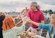 Gruppe von Menschen stößt gemeinsam an - Zacharie Scheurer/dpa-tmn