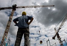 Mann blickt auf einer Baustelle auf zwei Kräne - Daniel Bockwoldt/dpa/dpa-tmn