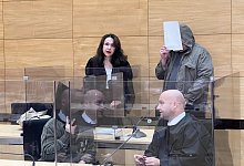 Nils T. hält sich erneut einenAktendeckel vor sein Gesicht, als er von Wachtmeistern neben seinerAnwältin Anne Patsch ins Gericht geführt wird. - Wolfgang Wotke