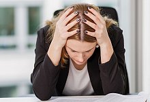 Frau stützt erschöpft den Kopf in die Hände - Monique Wüstenhagen/dpa-tmn