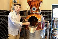 In einem großen, kupferfarbenen Kessel wird der edle Tropfen mit heimischen Kräutern wie Brombeeren, Haferstroh oder Gänseblümchen gebrannt. - Oliver Gierens/dpa