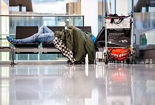 Mann schläft am Münchner Flughafen auf einer Sitzbank - Matthias Balk/dpa/dpa-tmn