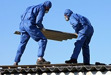 Arbeiter in Schutzkleidung demontieren Asbestplatten auf Dach - Bernd Wüstneck/dpa-Zentralbild/dpa-tmn