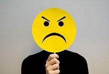 Eine Person hält sich ein Schild mit einer Fratze vor das Gesicht - Karolina Rezac/dpa-tmn