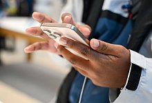 Ein Mann hält ein iPhone 16 in den Händen - Katharina Kausche/dpa/dpa-tmn