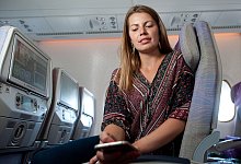 Eine Frau nutzt ihr Smartphone an Bord eines Flugzeugs - Klaus-Dietmar Gabbert/dpa-tmn