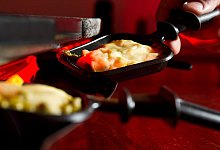 Mann h&auml;lt ein Raclette-Pf&auml;nnchen in der Hand - Franziska Gabbert/dpa-tmn
