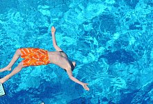 Junge springt vom Strungbrett in das Becken eines Freibads - Julian Stratenschulte/dpa/dpa-tmn