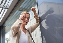 Frau mit Schwindelanfall st&uuml;tzt sich an einer Hauswand ab - Christin Klose/dpa-tmn