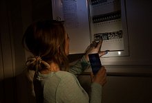 Frau schaut während eines Stromausfalls in den Sicherungskasten - Christin Klose/dpa-tmn