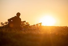 Mann spielt Gitarre im Licht der Sonne - Sebastian Gollnow/dpa/dpa-tmn