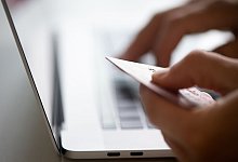 Mann sitzt mit Kreditkarte vor einem Laptop - Franziska Gabbert/dpa-tmn