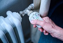 Eine Person dreht an einem Thermostat - Annette Riedl/dpa/dpa-tmn