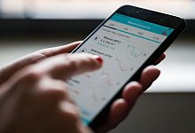 Frau bedient Kryptow&auml;hrungshandel-App - Marijan Murat/dpa/dpa-tmn