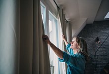 Eine Frau schliesst Vorhänge in einer Dachgeschosswohnung - Zacharie Scheurer/dpa-tmn