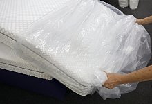 Entfernen der Folie von einer Matratze - Foto: Wolfgang Kumm