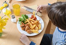 Ein Kind isst Chicken Nuggets und Pommes Frites - Tobias Hase/dpa/dpa-tmn
