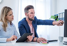 Kollegen blicken auf einen Monitor - Christin Klose/dpa-tmn