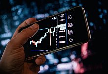 Mann schaut sich Aktienkurse auf dem Smartphone an - Zacharie Scheurer/dpa-tmn